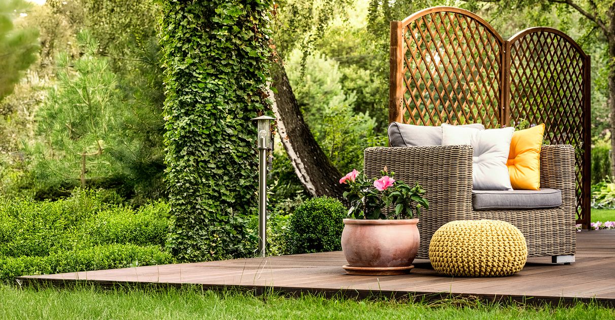 Wickerstuhl auf einer Terrasse, daneben ein Topf mit einer grünen Pflanze